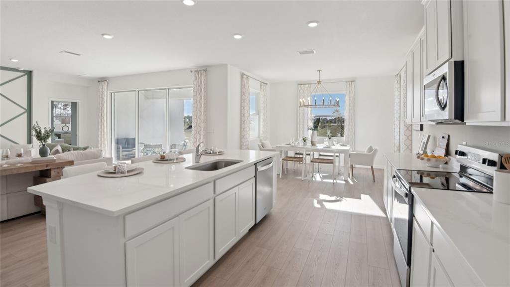 A bright, open-concept kitchen features a large white quartz island and light wood flooring — 12728 NW 17TH PLACE, NEWBERRY, FL