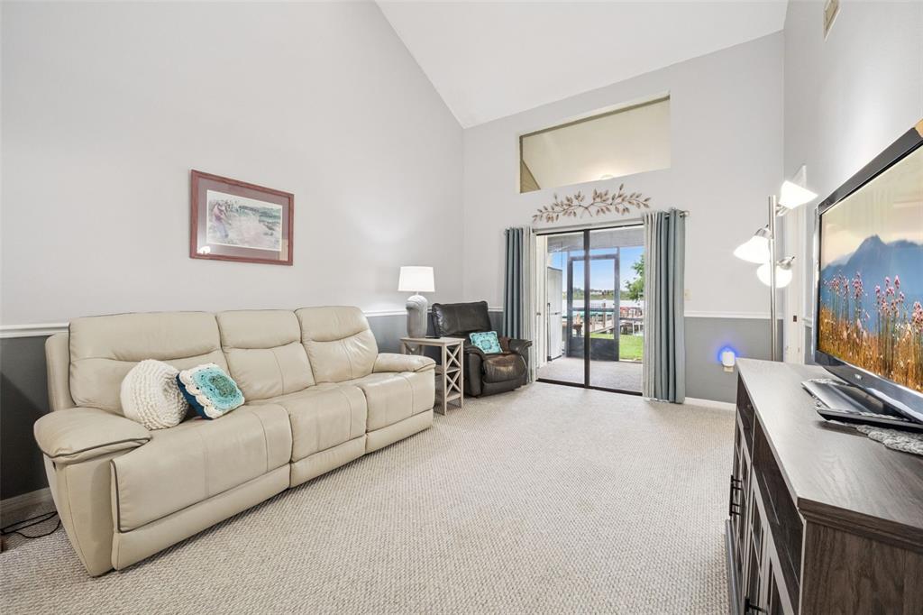 A living room features a beige sofa, a dark recliner, and a sliding glass door — 2600 LUCERNE PARK ROAD UNIT 521, WINTER HAVEN, FL