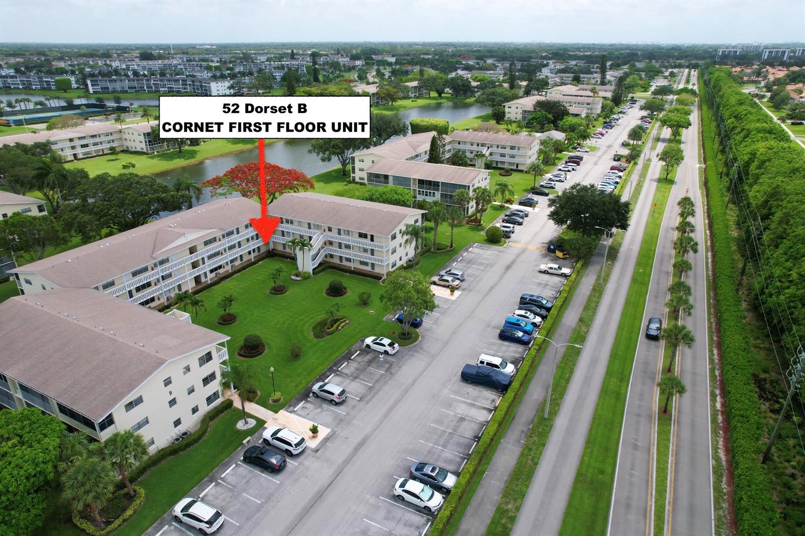 An aerial view shows a multi-story apartment building with a grassy courtyard and parking lot — 52 Dorset Drive # B, Boca Raton FL 33434, BOCA RATON, FL