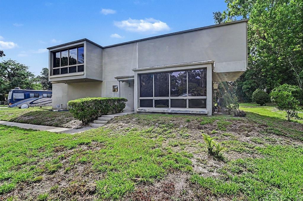 A two-story modern house with large windows and a flat roof sits on a lawn — 633 S DELAWARE AVENUE, DELAND, FL