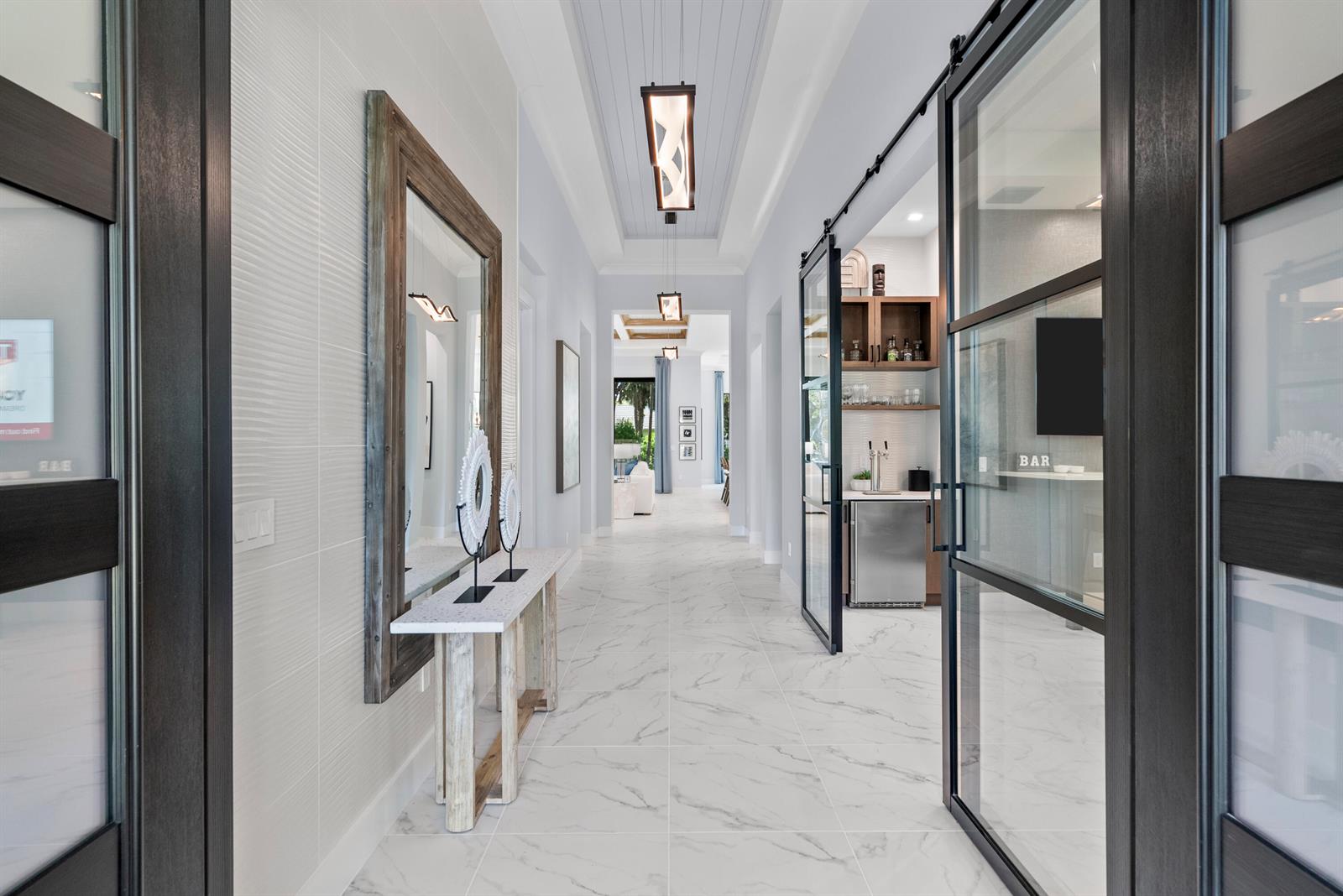 A bright hallway features marble-look tile floors, a console table with a mirror, and glass doors — 9259 Seaglass Court, Vero Beach FL 32963, VERO BEACH, FL