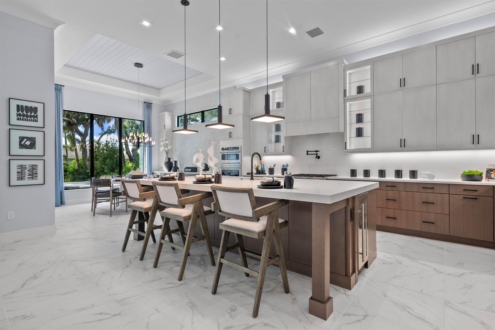 A modern kitchen features a large island with bar seating, light cabinetry, and marble flooring — 9259 Seaglass Court, Vero Beach FL 32963, VERO BEACH, FL
