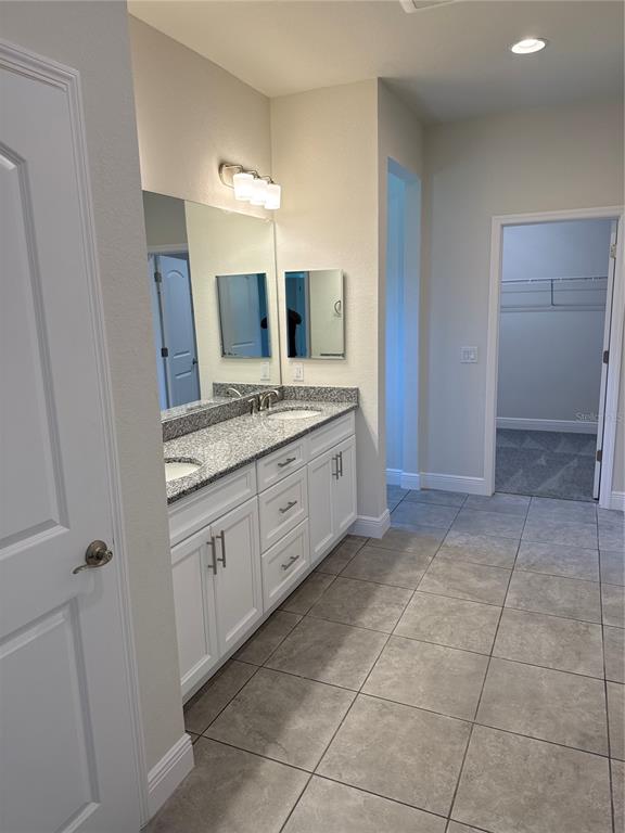 A bathroom features a double vanity with white cabinets, granite countertops, and a walk-in closet — 5372 JODY AVENUE, NORTH PORT, FL