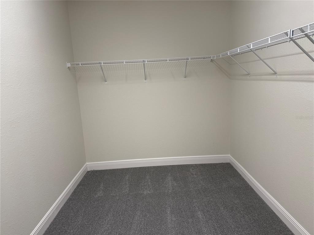 A walk-in closet features gray carpeting and white wire shelving mounted on the walls — 5372 JODY AVENUE, NORTH PORT, FL