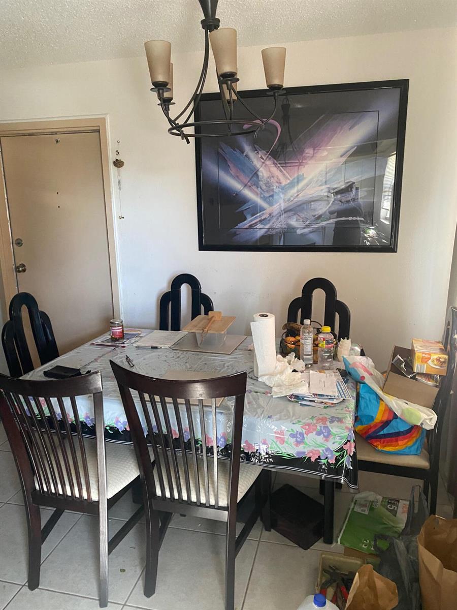 A dining room features a dark wood table with chairs, a chandelier, and wall art — 668 Monaco N # 668, Delray Beach FL 33446, DELRAY BEACH, FL