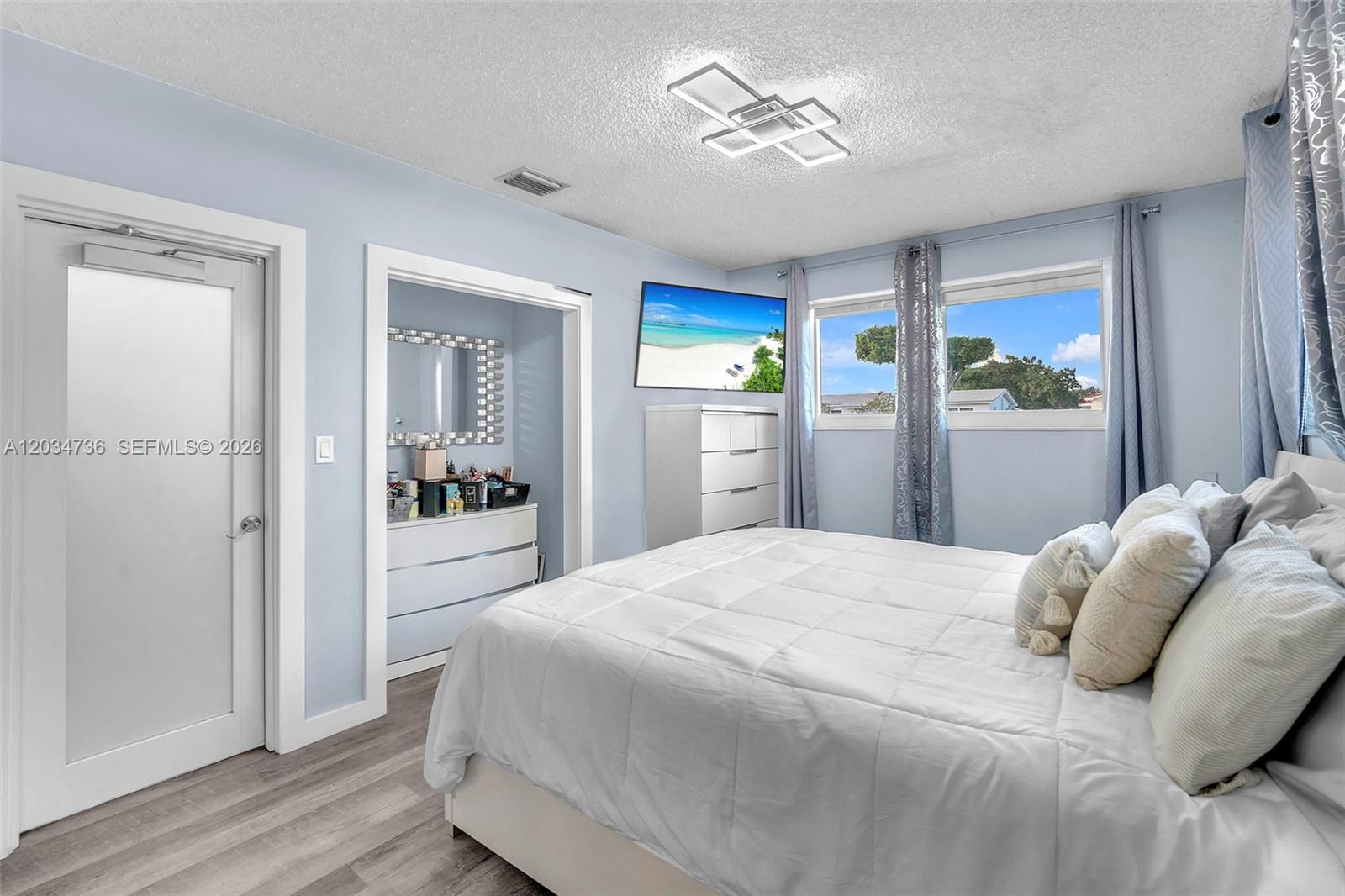 A bedroom features light blue walls, a white bed, a dresser, and a closet — 380 W 30th St, Hialeah FL 33012, HIALEAH, FL