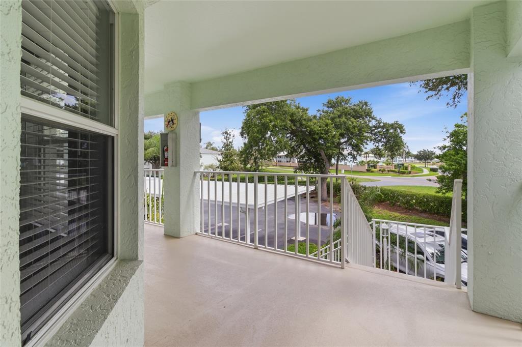 A covered balcony with white railings overlooks a parking area and a landscaped neighborhood — 5725 GREENWOOD AVENUE UNIT 1201, NORTH PORT, FL