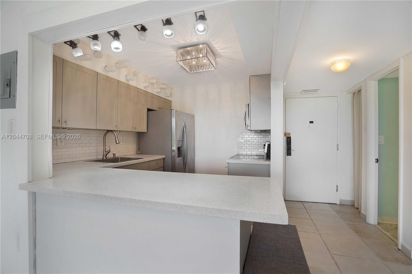 A kitchen features light wood cabinets, a white countertop, stainless steel appliances, and track lighting — 6900 Bay Dr # 3H, Miami Beach FL 33141, MIAMI BEACH, FL