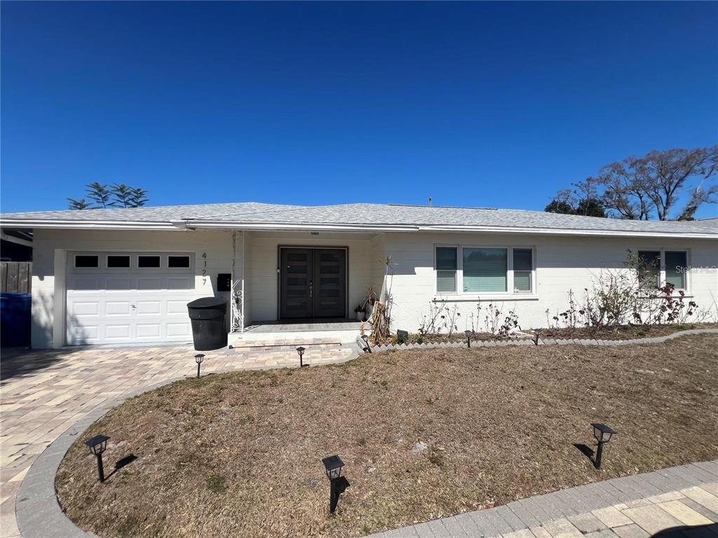 A single-story white house with a paved driveway, a garage, and a front lawn — 4127 28TH AVENUE N, ST PETERSBURG, FL
