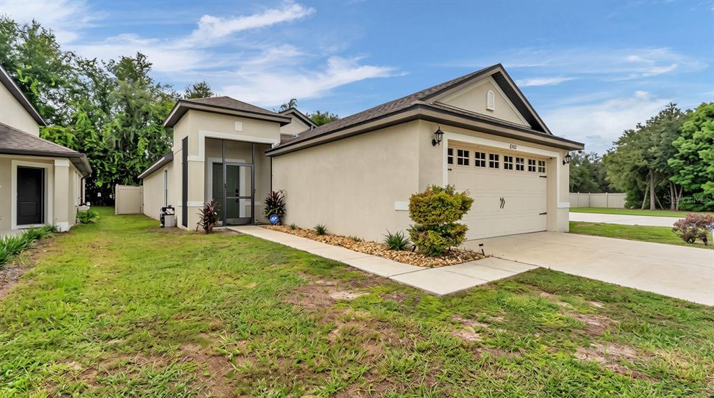 A beige single-story house with a two-car garage and a screened front entryway — 6302 MANITOBA DRIVE, LAKELAND, FL