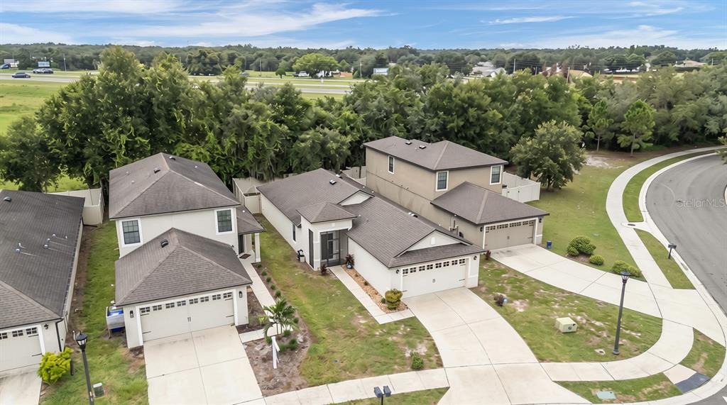 An aerial view shows three suburban houses with driveways and lawns near a curved road — 6302 MANITOBA DRIVE, LAKELAND, FL