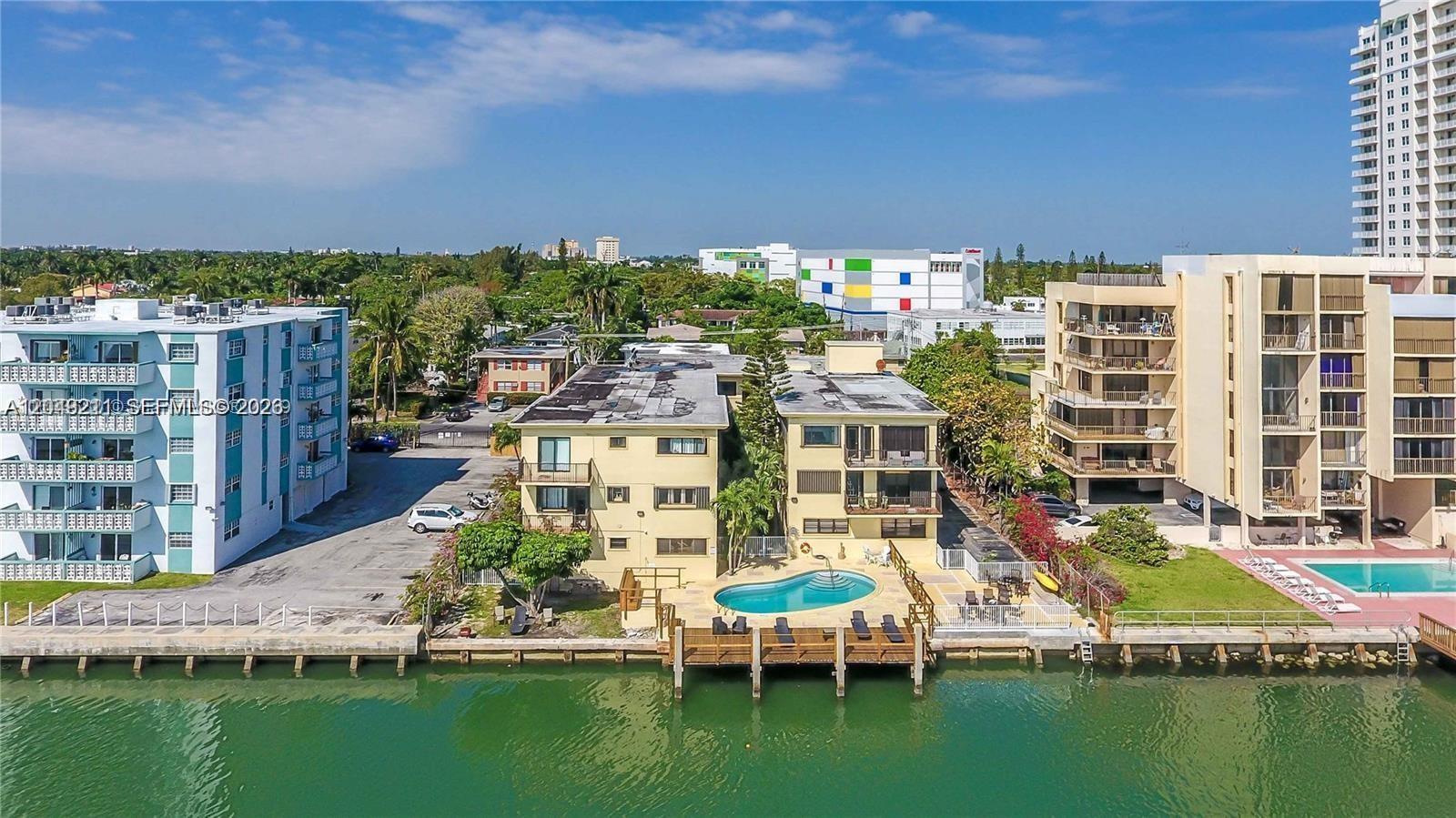 An aerial view shows waterfront apartment buildings with a swimming pool and wooden docks — 7845 NE Bayshore Ct # 8, Miami FL 33138, MIAMI, FL