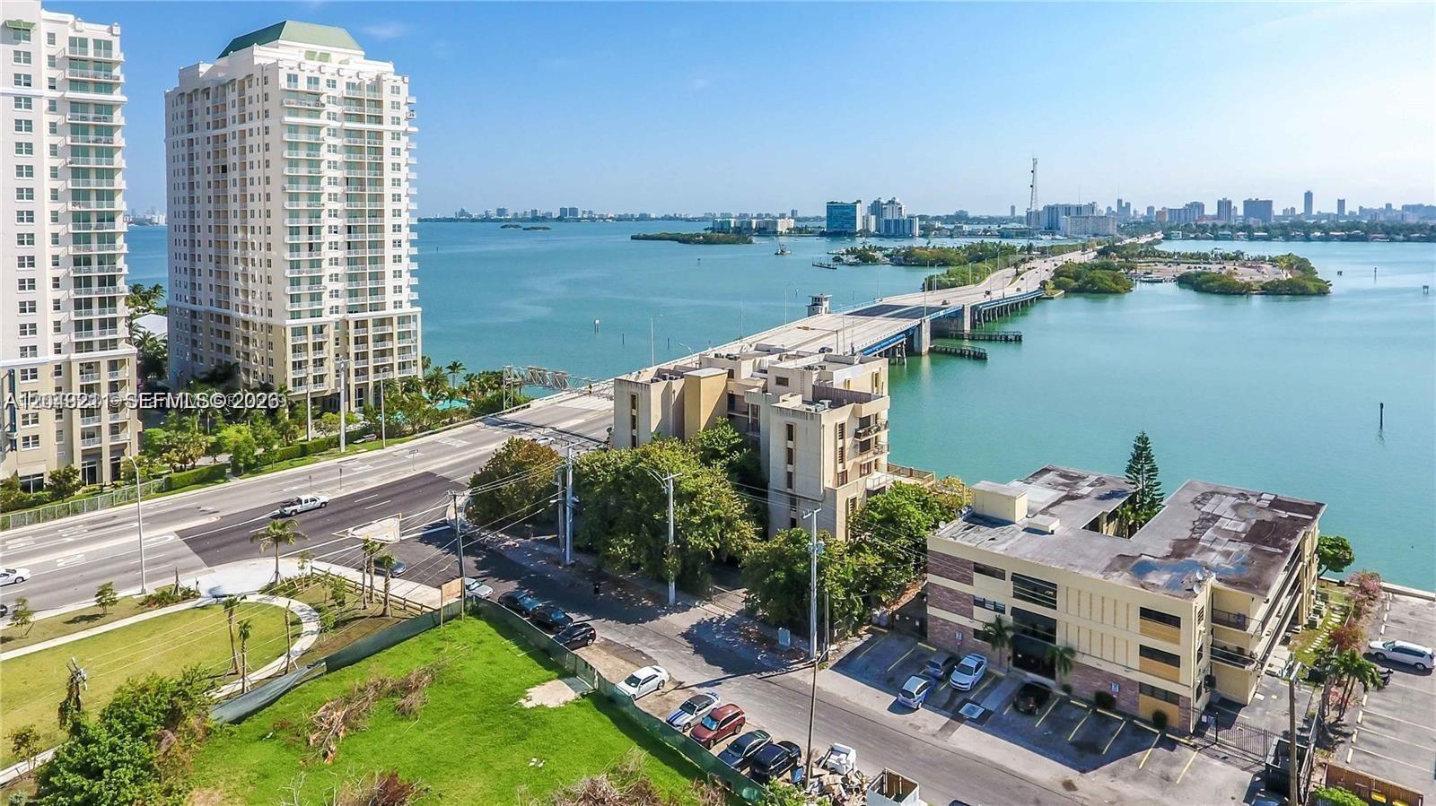 An aerial view shows a multi-story residential building, a bridge, and a coastal waterway — 7845 NE Bayshore Ct # 8, Miami FL 33138, MIAMI, FL