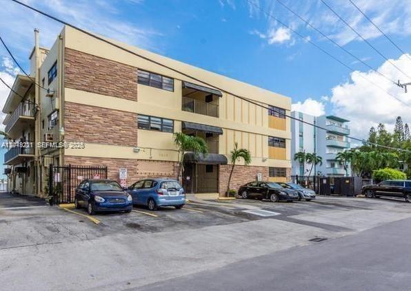 An exterior view of a three-story apartment building with stone accents and a parking lot — 7845 NE Bayshore Ct # 8, Miami FL 33138, MIAMI, FL