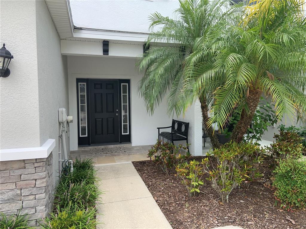 A concrete walkway leads to a black front door with sidelights under a covered entryway — 6461 BAYTOWN DRIVE, SARASOTA, FL