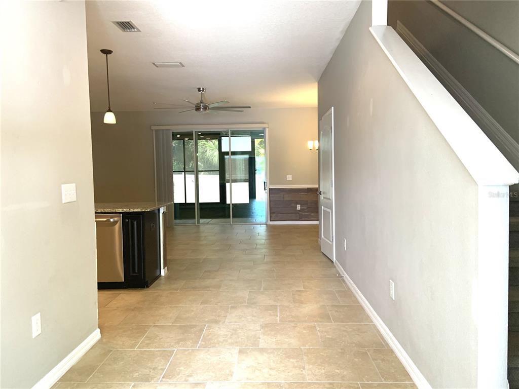 A view from a hallway looking toward a kitchen, living area, and sliding glass doors — 6461 BAYTOWN DRIVE, SARASOTA, FL