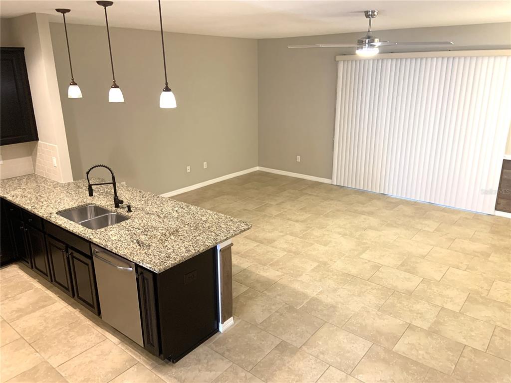 A kitchen island with granite countertops and dark cabinets sits in an open-concept living area — 6461 BAYTOWN DRIVE, SARASOTA, FL