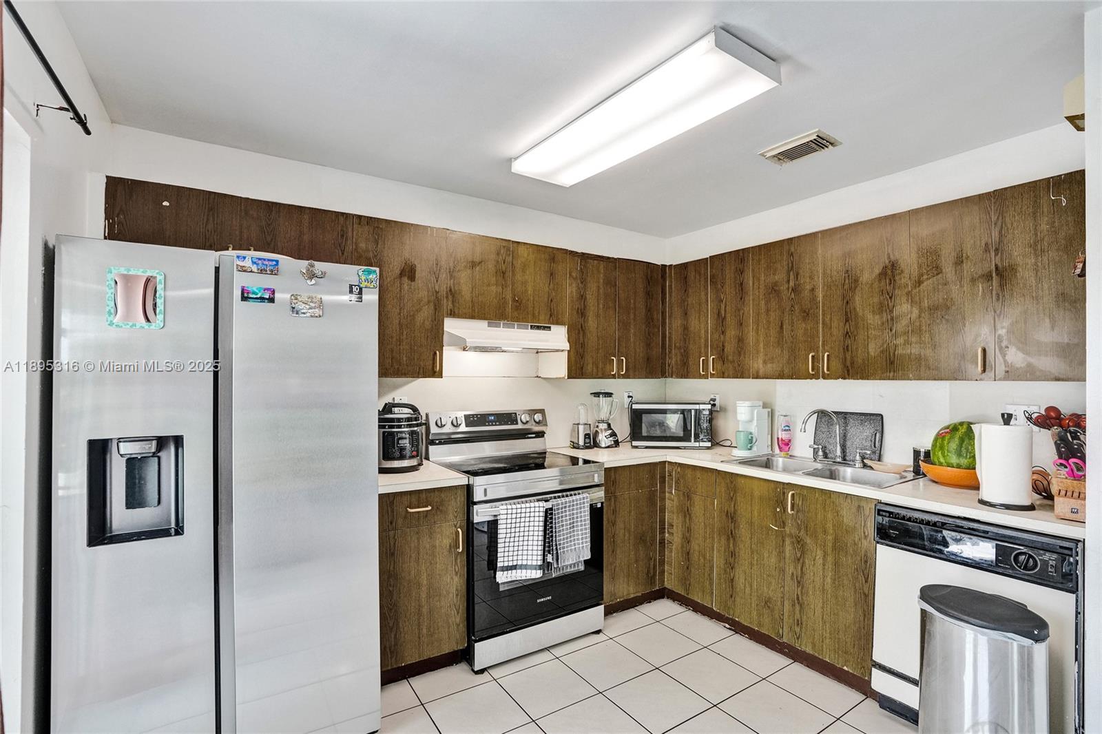 A kitchen features wood-grain cabinets, stainless steel appliances, and white tile flooring — 13780 SW 160th Ter, Miami FL 33177, MIAMI, FL