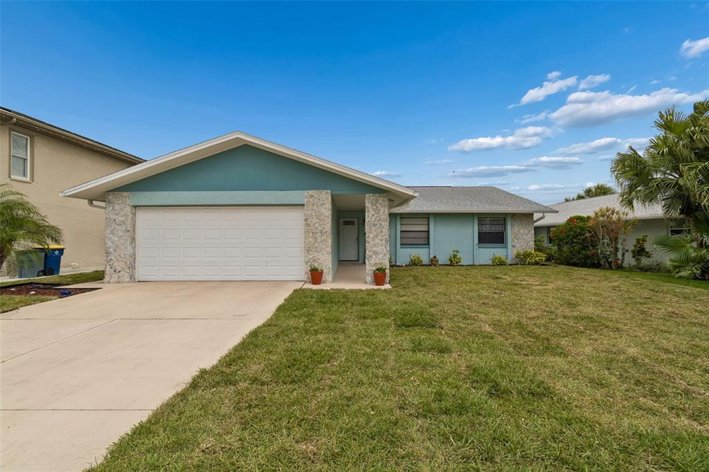 A single-story house with a light blue exterior, stone accents, and a two-car garage — 5440 LEAHY LANE, NEW PORT RICHEY, FL