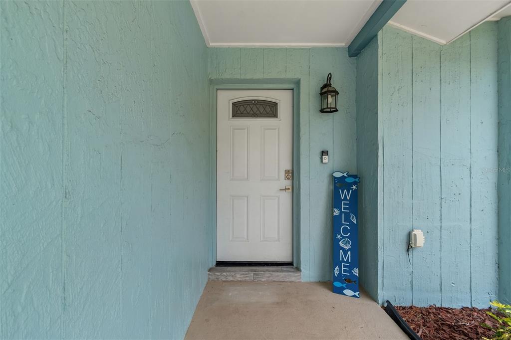A light blue exterior entryway features a white front door and a decorative welcome sign — 5440 LEAHY LANE, NEW PORT RICHEY, FL