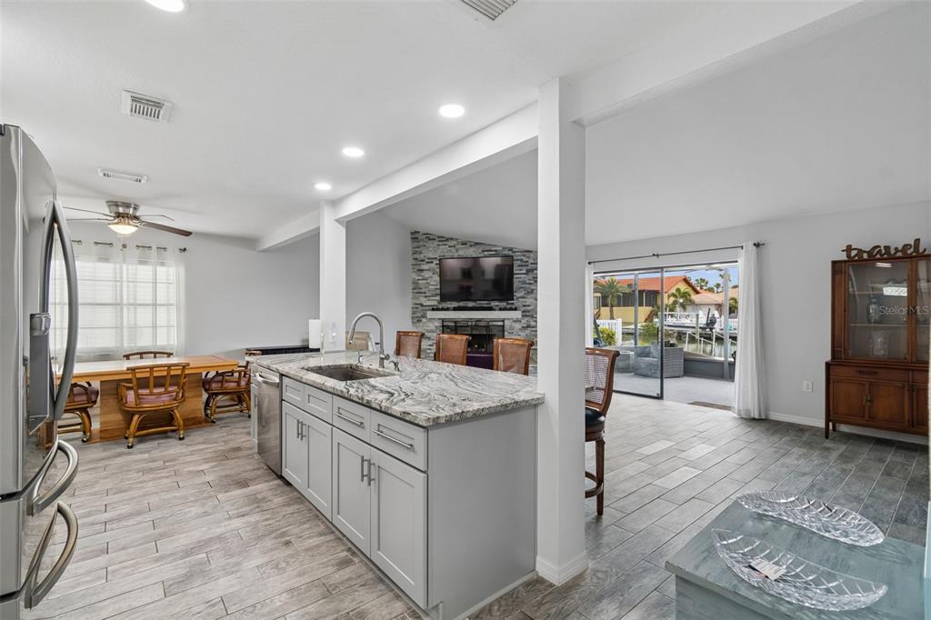 A kitchen with gray cabinets and granite countertops overlooks a living area and outdoor patio — 5440 LEAHY LANE, NEW PORT RICHEY, FL
