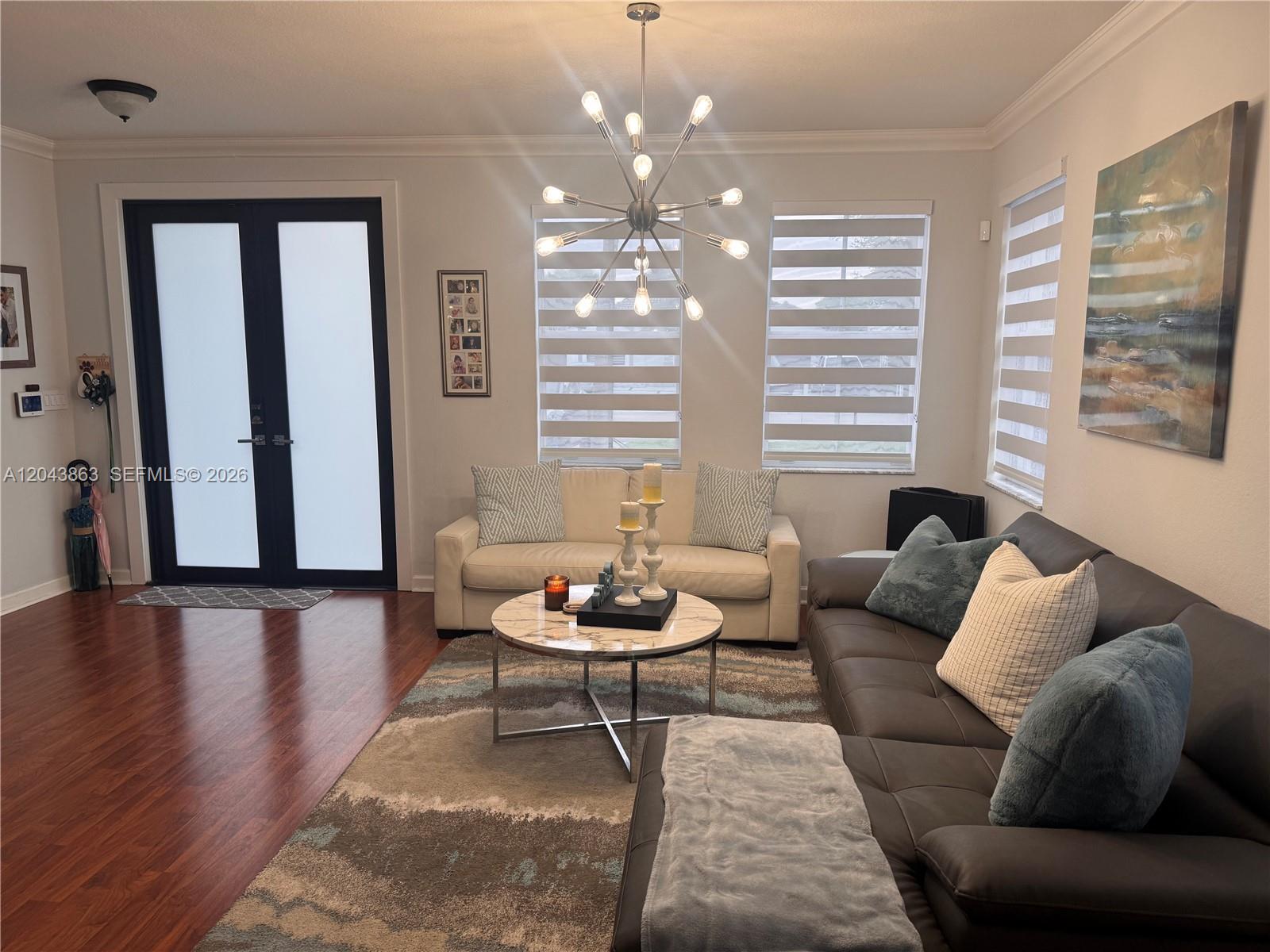 A living room features a dark leather sectional, a white sofa, and a modern chandelier — 15376 SW 13th Ter, Miami FL 33194, MIAMI, FL