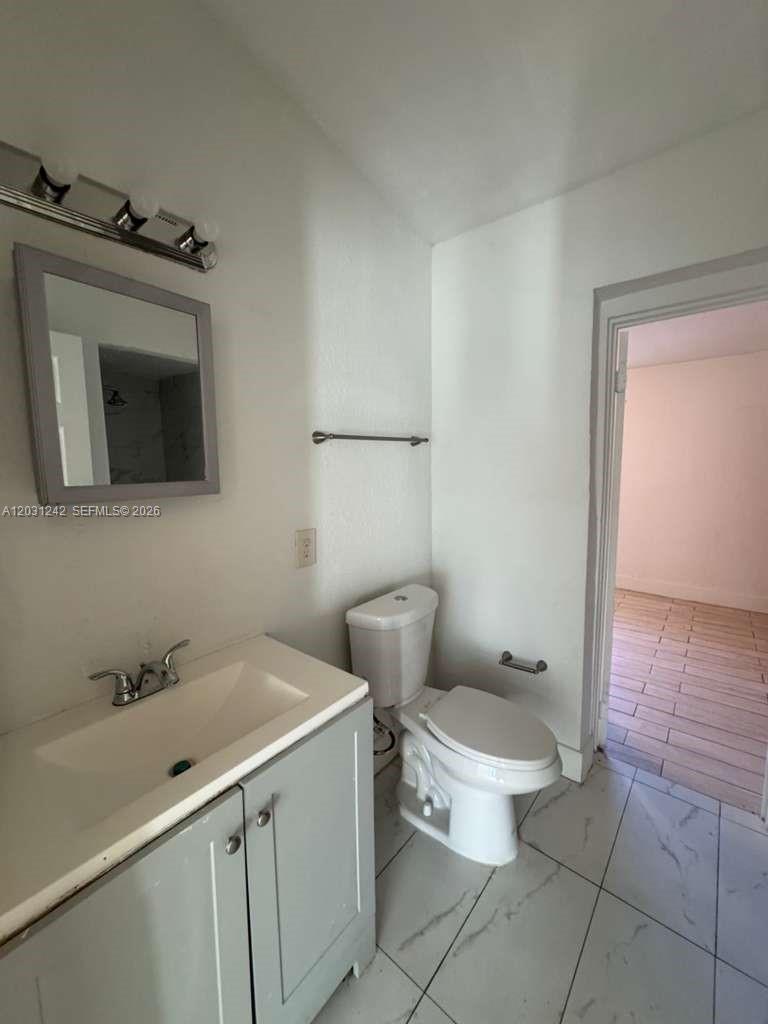 A bathroom features a light gray vanity, a white toilet, and a wall-mounted mirror — RIVIERA BEACH, FL