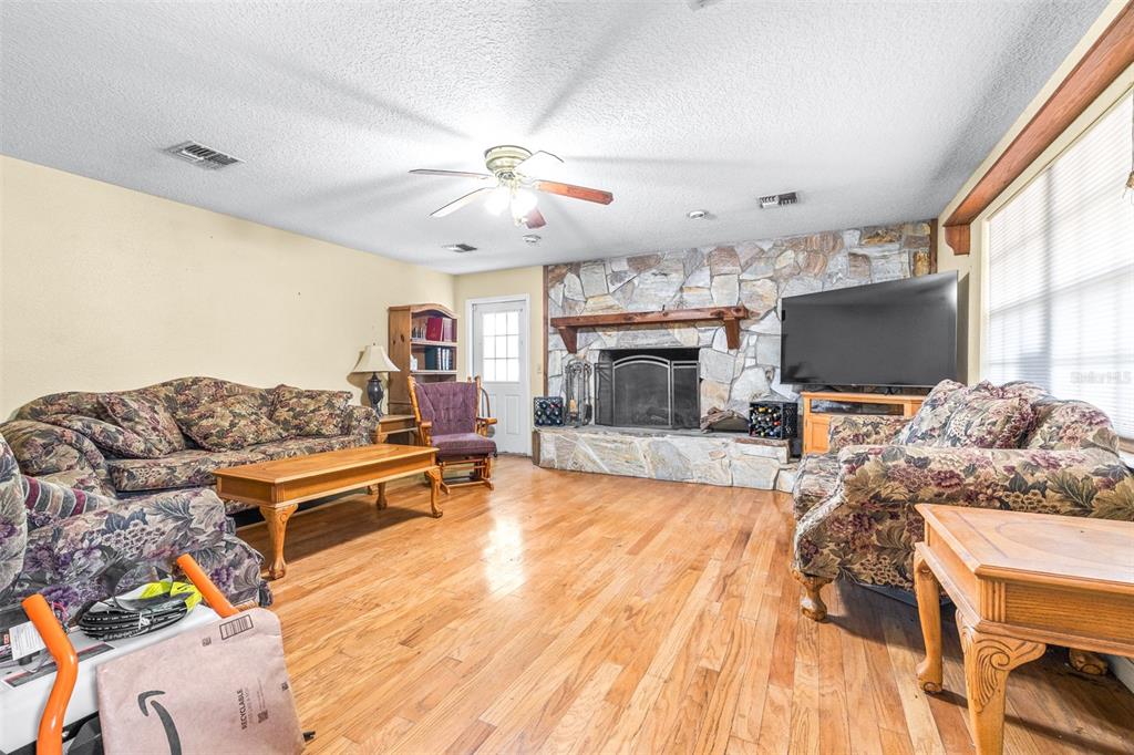 A living room features a stone fireplace, floral sofas, and hardwood floors — 954 ODONIEL DRIVE, LAKELAND, FL