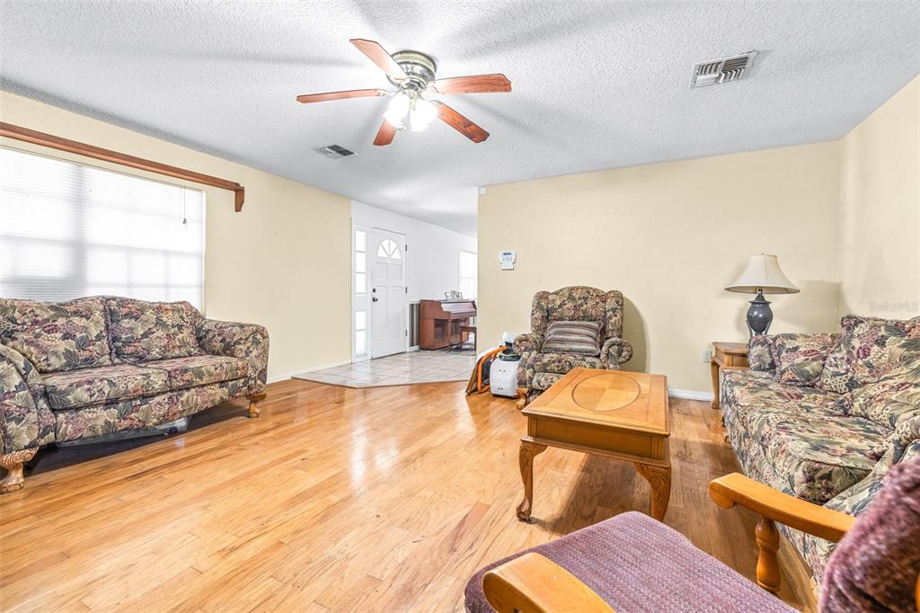 A living room features floral sofas, a wooden coffee table, and hardwood flooring — 954 ODONIEL DRIVE, LAKELAND, FL