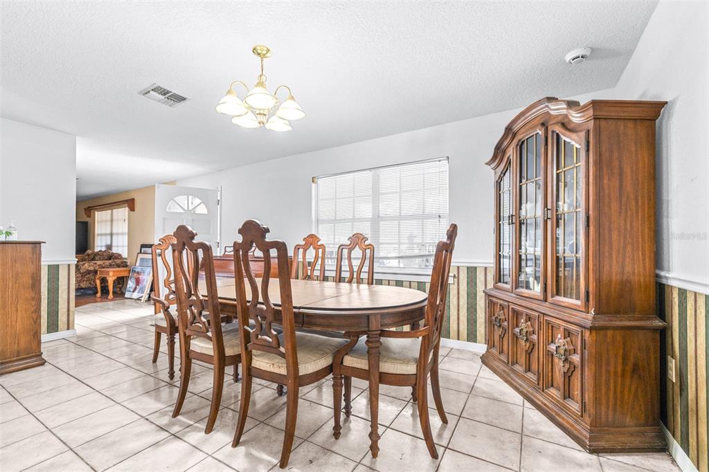 A dining room with a wooden table, chairs, and a large hutch on tiled flooring — 954 ODONIEL DRIVE, LAKELAND, FL