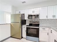 A kitchen featuring white cabinets, stainless steel appliances, and a refrigerator next to the stove — 1591 REVERE LANE, DAYTONA BEACH, FL