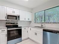 A kitchen features white cabinets, stainless steel appliances, and a window above the sink — 1591 REVERE LANE, DAYTONA BEACH, FL
