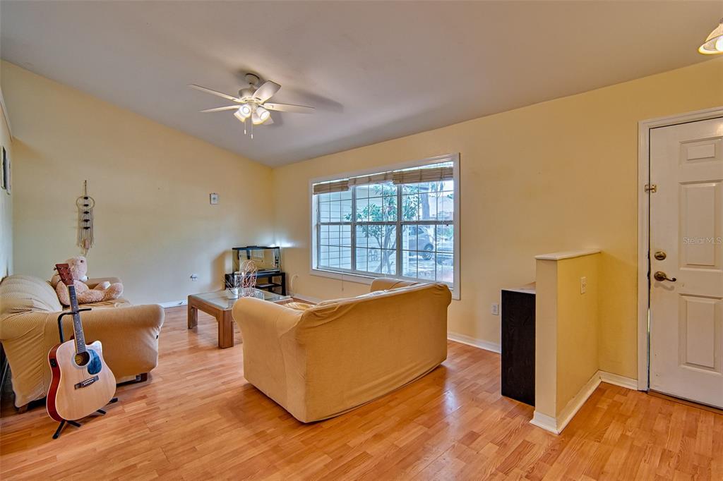 A living room with light yellow walls, wood flooring, two beige sofas, and a ceiling fan — 7605 SW 51ST BOULEVARD, GAINESVILLE, FL