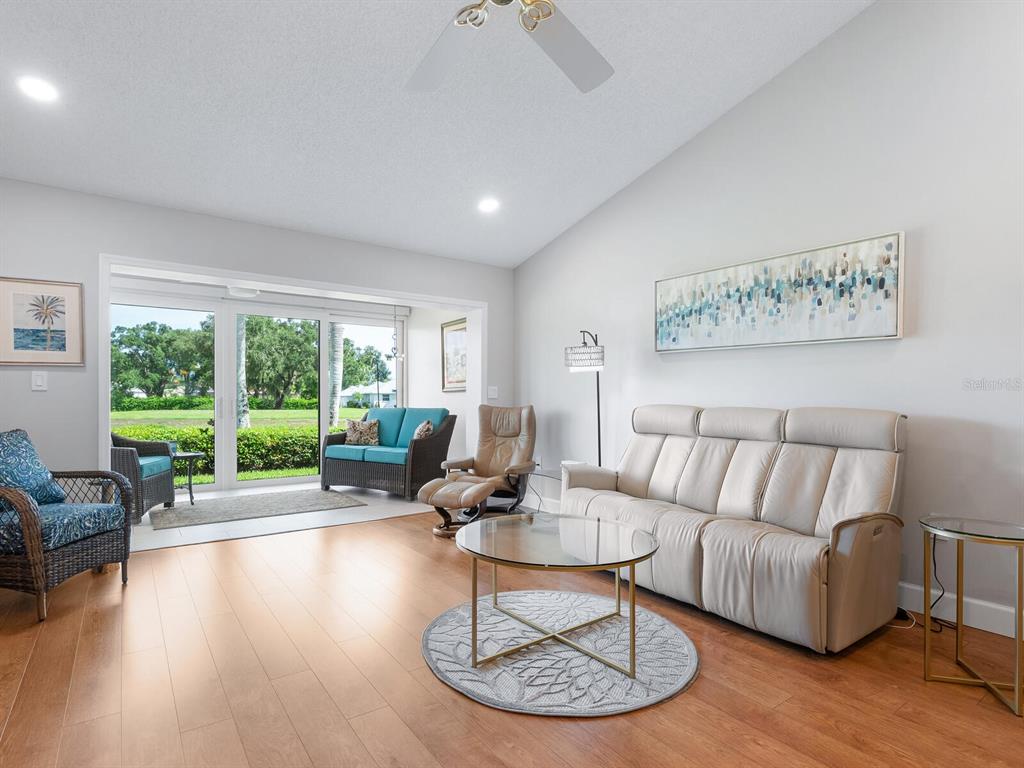 A living room features light wood flooring, a beige reclining sofa, and sliding glass doors — 6103 CLUBSIDE DRIVE UNIT 6103, SARASOTA, FL