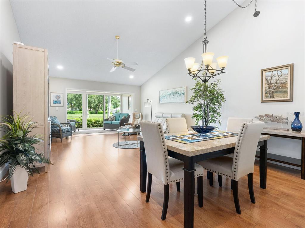 A dining area with a stone-topped table opens into a living room with sliding doors — 6103 CLUBSIDE DRIVE UNIT 6103, SARASOTA, FL