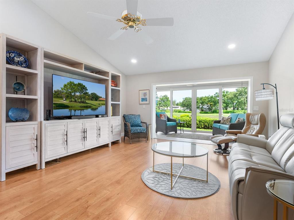 A living room with light wood floors, a large entertainment center, and sliding glass doors — 6103 CLUBSIDE DRIVE UNIT 6103, SARASOTA, FL
