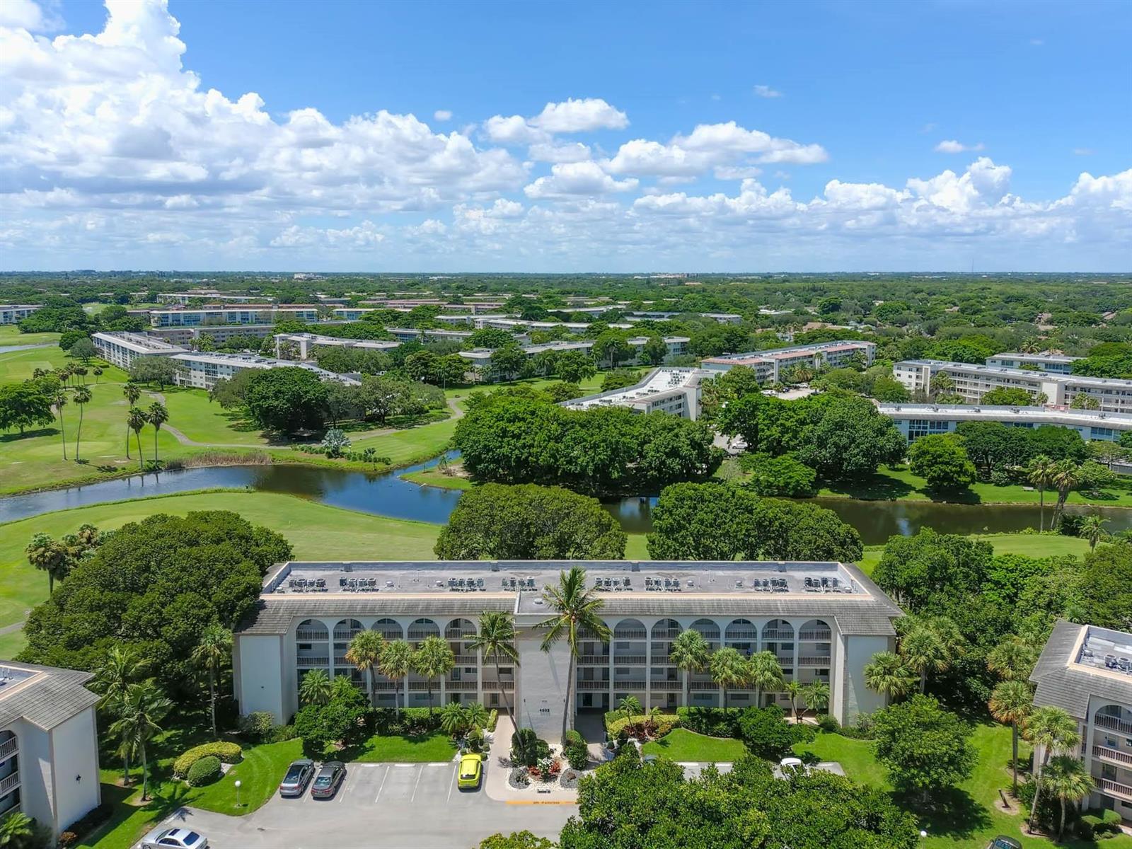 An aerial view shows a multi-story apartment building surrounded by a golf course and trees — 4502 Martinique Way # E1, Coconut Creek FL 33066, COCONUT CREEK, FL