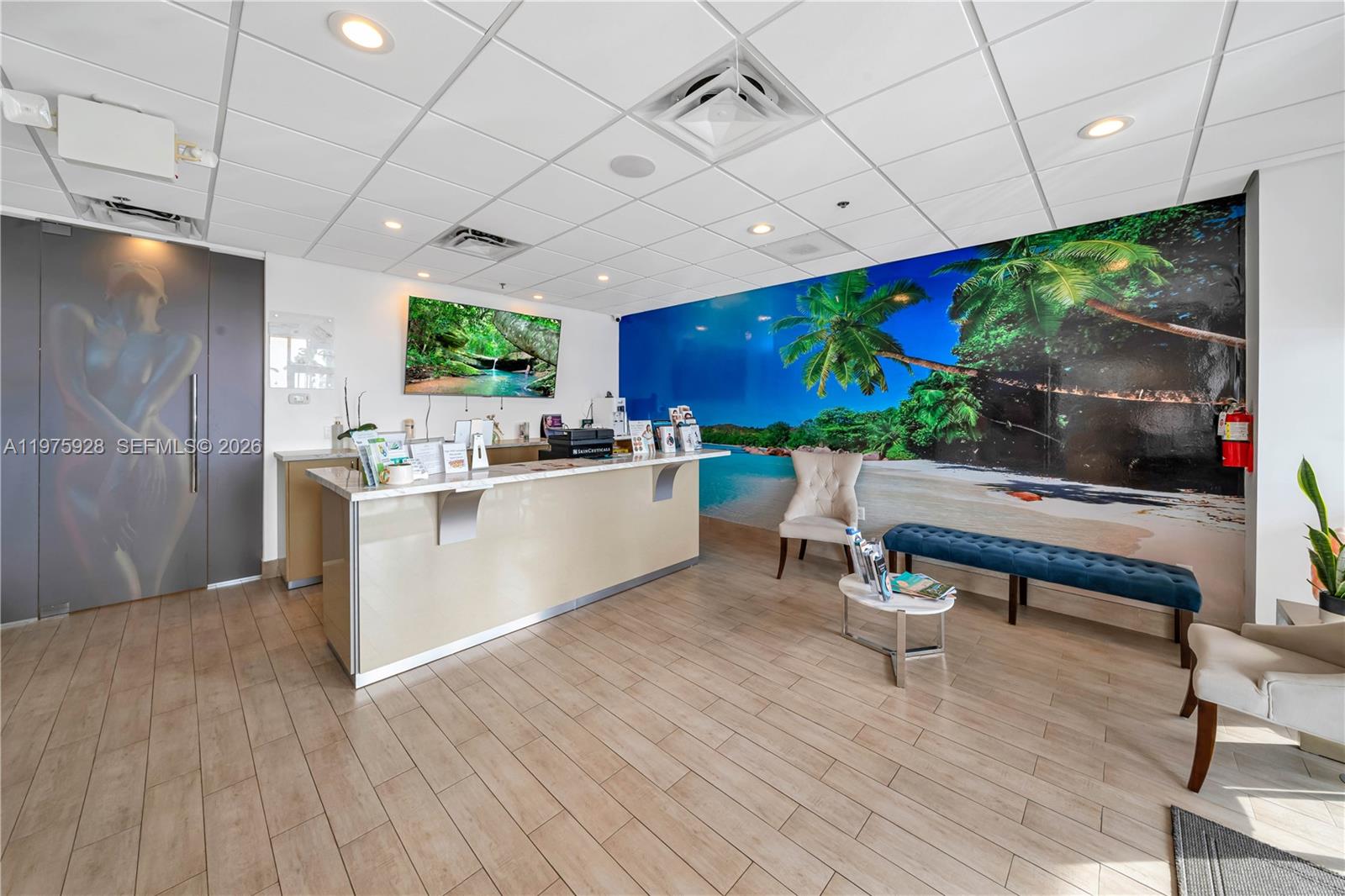 A reception area features a long desk, a beach mural, and a blue bench — 3749 NE 163, FL 33160, FL