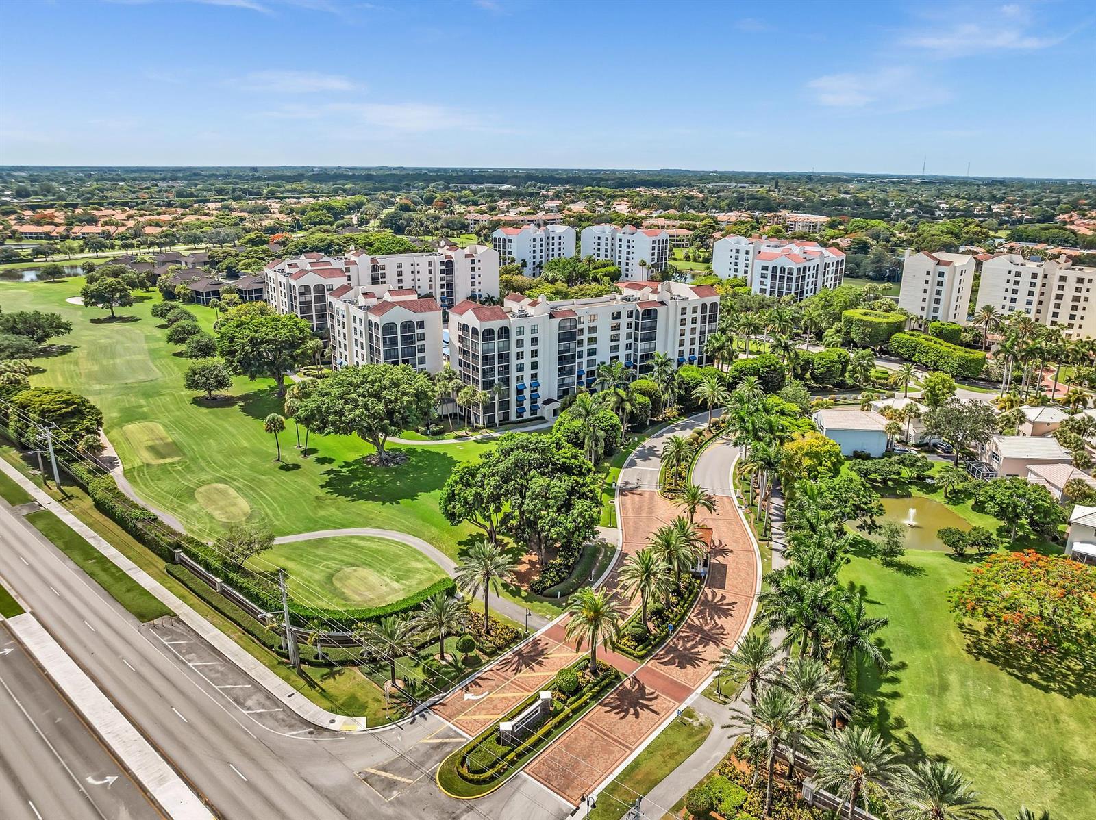 An aerial view shows a multi-story apartment complex surrounded by a golf course and trees — 7564 Regency Lake Drive # 202, Boca Raton FL 33433, BOCA RATON, FL