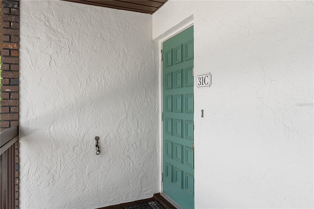 A green front door with the number 31C is set into a white stucco wall — 3 CYPRESS RUN UNIT 31C, HOMOSASSA, FL