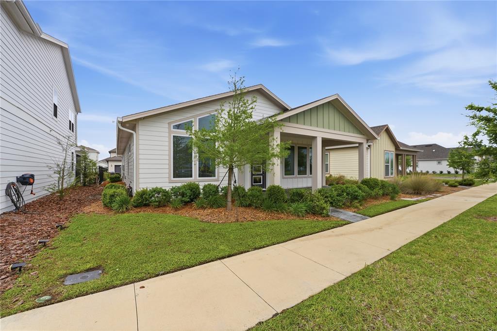 A single-story house with light siding, a covered front porch, and a landscaped front yard — 6550 BARNSTORM WAY, ST CLOUD, FL