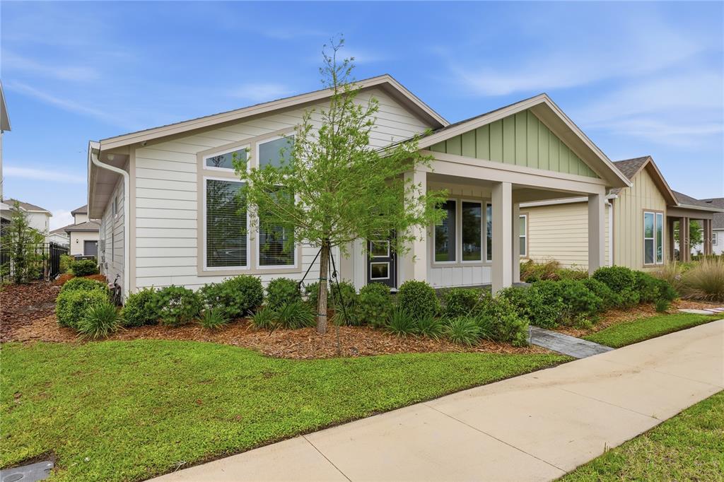 A single-story house with white horizontal siding, a covered front porch, and a green gable — 6550 BARNSTORM WAY, ST CLOUD, FL