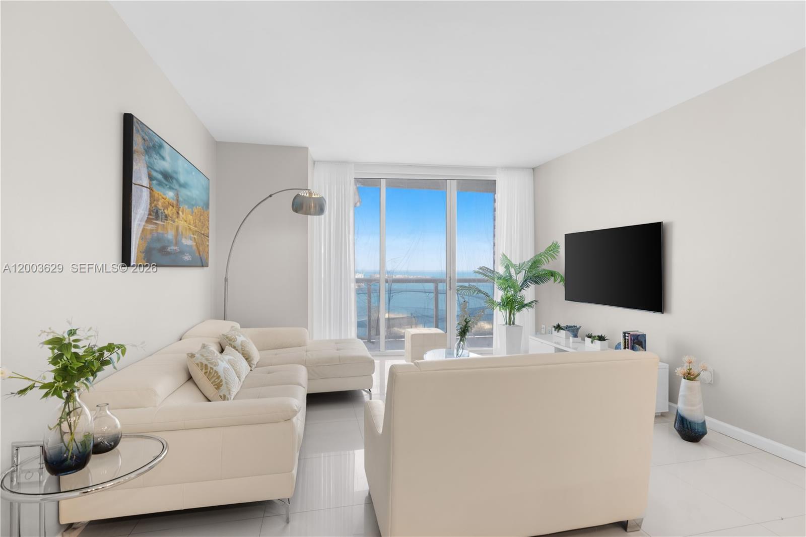 A bright living room features a white sectional sofa, a wall-mounted television, and floor-to-ceiling windows — 485 Brickell Ave # 4501, Miami FL 33131, MIAMI, FL