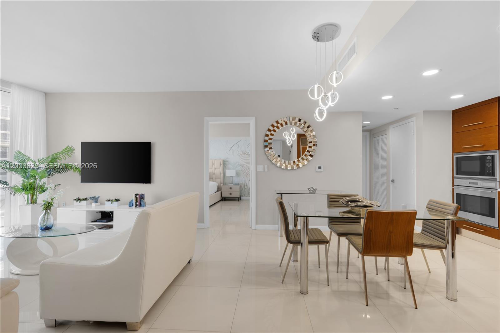 A modern living and dining area features white tile floors, a glass table, and cabinetry — 485 Brickell Ave # 4501, Miami FL 33131, MIAMI, FL