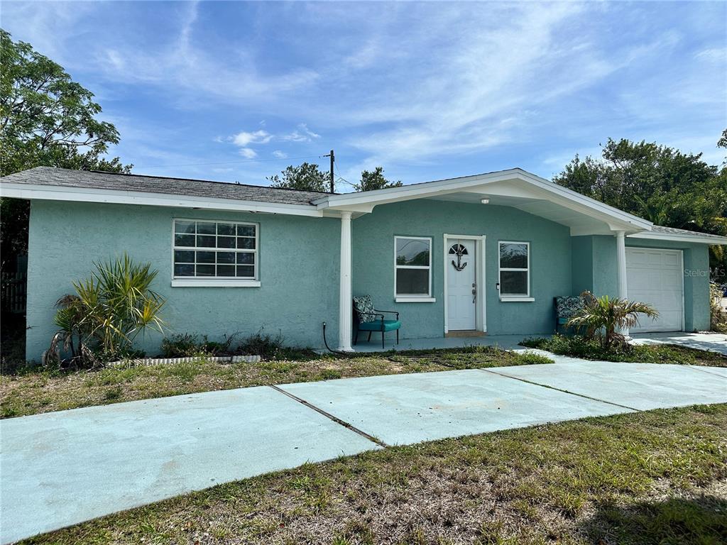 A light blue single-story house features a white front door, a garage, and a driveway — 3240 BRIAR CLIFF DRIVE, HOLIDAY, FL