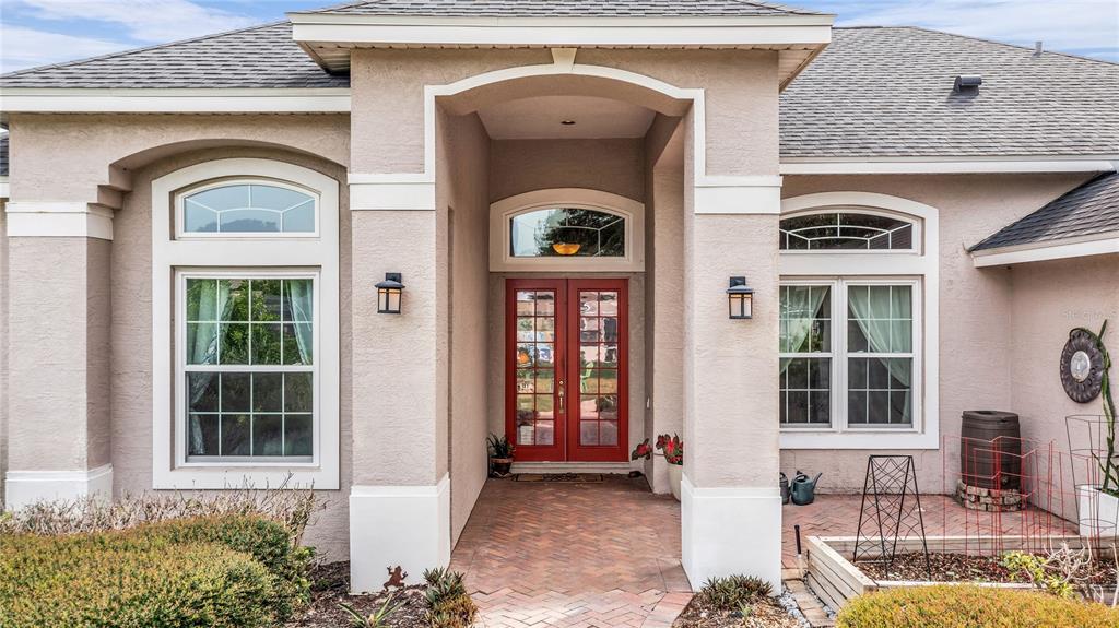 The exterior of a beige house features a brick walkway leading to red double doors — 9113 IVEY HILL COURT, ORLANDO, FL
