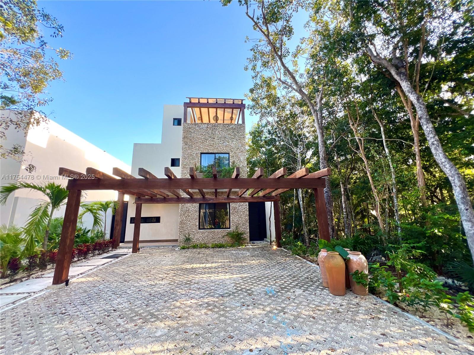 A modern house features a stone facade, a wooden pergola, and a paved driveway — Kaybe Tulum Kaybe Tulum, TX 77760, TX