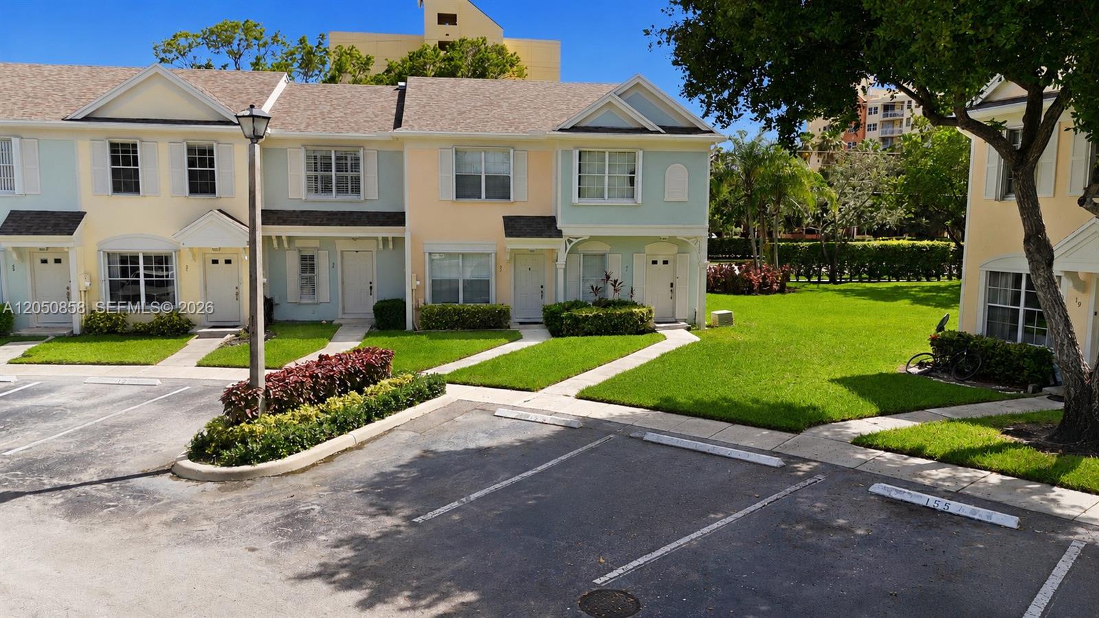 A row of multi-story townhouses with pastel siding and a parking lot in the foreground — 21 Simonton Cir, Weston FL 33326, WESTON, FL