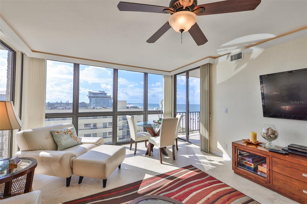 A living room with a beige sofa, dining set, and floor-to-ceiling windows overlooking the ocean — 5396 GULF BOULEVARD UNIT 701, ST PETE BEACH, FL