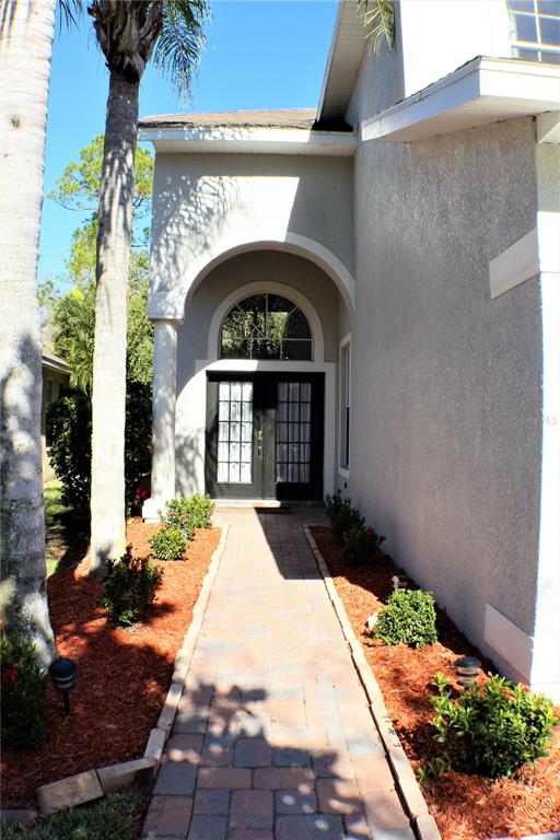 A paved walkway leads to the front entrance of a house with a covered porch — 11609 GREENSLEEVE AVENUE, TAMPA, FL